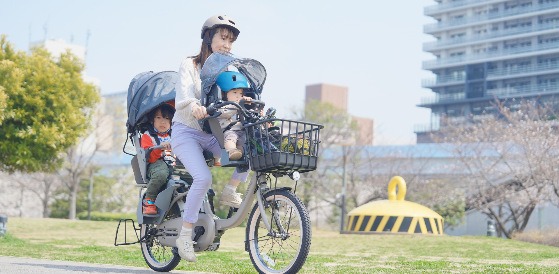 子供を自転車の後ろに乗せて歩いている母親