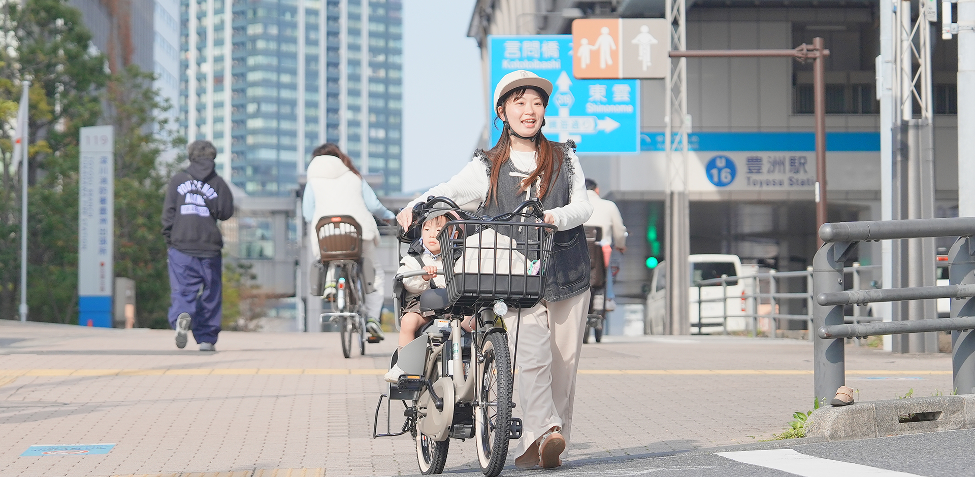 子供を自転車の後ろに乗せて歩いている母親